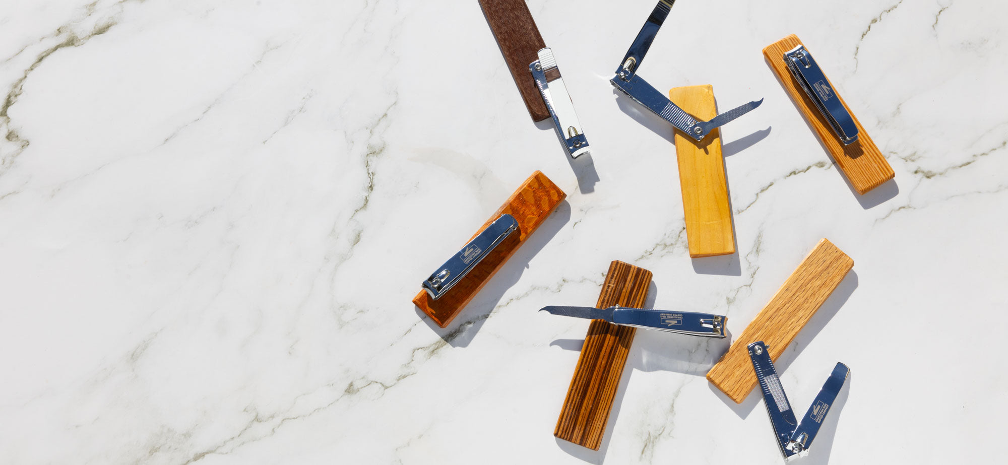 Various hand-crafted fingernail & toenail clippers showcasing versatile functionality laying on marble. 